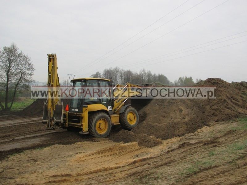 Maszyna rozplantowująca ziemię przy niwelacji działki w okolicach Częstochowy