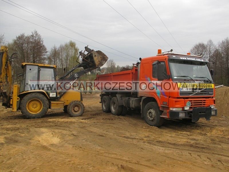 Koparko-ładowarka Caterpillar ładuje piasek na wywrotkę podczas robót ziemnych w Częstochowie